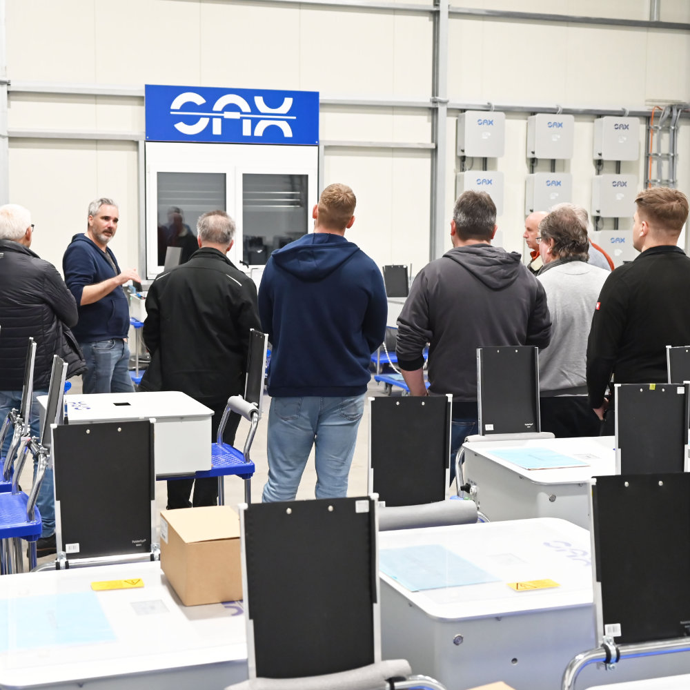 Ein Mitarbeiter des Speicher Herstellers SAX Power erklärt Elektrikern in der Versuchs halle des Herstellers die Funktion des SAX Stromspeichers